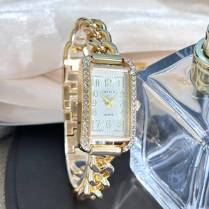 Detail of a gold rectangular women watch with crystal bezel on white silk backdrop