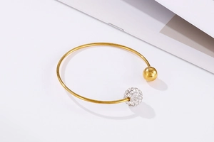 Gros plan sur le bracelet jonc doré en C avec une bille pavée de cristaux et une sphère polie
