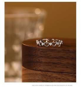 Detail of s925 silver hollow heart ring with zircon stones on a wooden stand