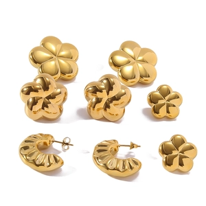Detail of 18K gold plated flower studs and textured C-shape hoop earrings on white