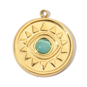 Detail of a gold sunburst pendant with a green gemstone eye and textured rays