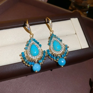 Detail of bohemian gold earrings with turquoise stones and blue beads in a gift box