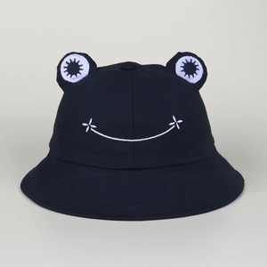 Detail of a black cotton bucket hat featuring 3D frog eyes and white embroidered smile