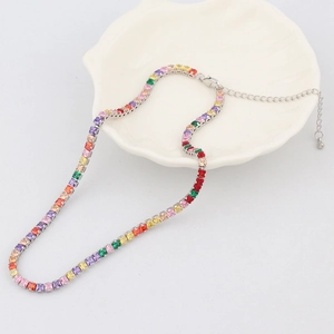 Detail of colorful zircon square tennis necklace with silver setting on a shell plate