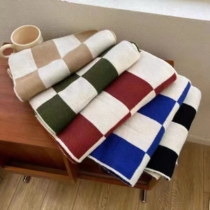 Close-up of neatly folded cashmere-like scarves in checkered patterns and ceramic cup