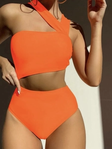 Detail of bright orange one-shoulder cutout bikini set with high-waisted bottoms