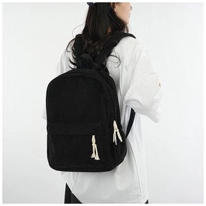 Detail view of black corduroy backpack on model showing large capacity and soft texture