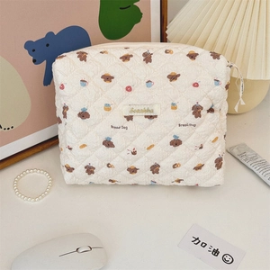 Detailed view of white quilted cosmetic bag featuring cute cartoon bread dog patterns