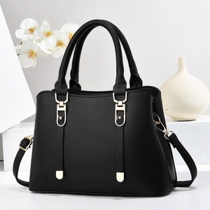 Detailed shot of black lychee grain leather handbag with elegant gold metal buckles