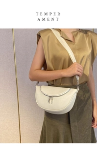 Detail view of cream crescent crossbody bag with lychee texture and silver double zippers