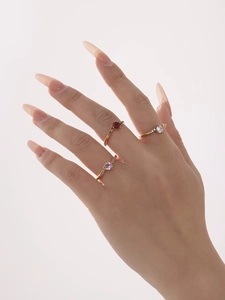 Detailed view of three 18k gold rings with red, purple and white zircon stones on model's hand