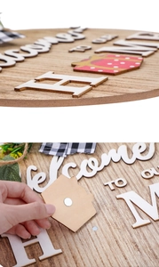 Close-up of wooden welcome home sign showing 3D letters and magnetic house attachment