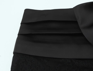 Detail of black satin and lace patchwork mini dress with handcrafted pleats