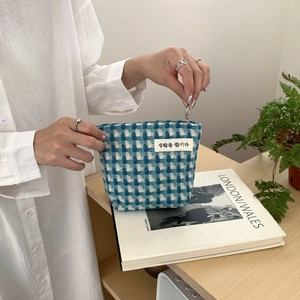 Détail d'une pochette en tissu à carreaux bleus avec étiquette coréenne et zip métallique