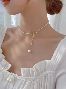 Close-up of pearl necklace featuring a golden bow pendant and elegant tassel detail