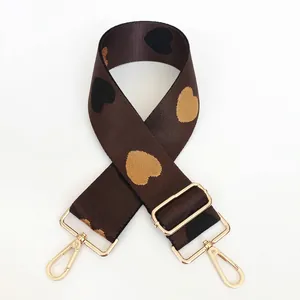 Detail of adjustable nylon bag strap with heart jacquard pattern and gold swivel hooks