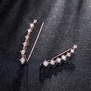 Detailed close-up of rose gold ear crawler featuring sparkling inlaid zircons on black background