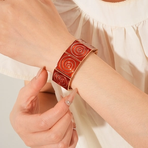 Close-up of red enamel bracelet with swirl texture on woman's wrist