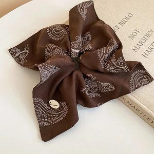 Detail of dark brown paisley satin hair scrunchie with decorative white button accent