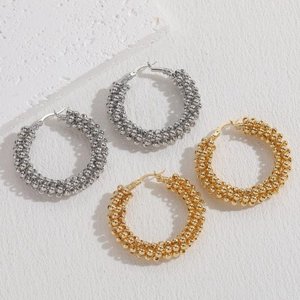 Twisted bead texture hoop earrings in gold and silver finish on stone background