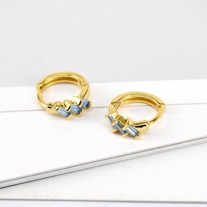 Detail of gold hoop earrings featuring three light blue rectangular zircon stones