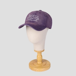 Détail de la casquette de baseball en coton délavé violet avec broderie blanche sur mannequin