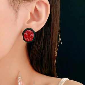 Détail des boucles d'oreilles géométriques rouges et noires portées par un mannequin