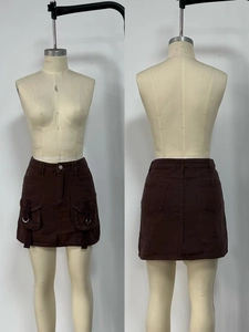 Detail of high waist brown denim mini skirt with utility cargo pockets and side strap