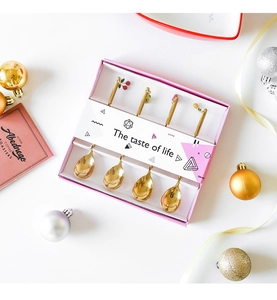 Set of four gold Christmas coffee spoons in a pink gift box with festive decorations