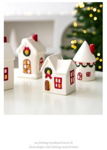 Detail view of ivory ceramic Christmas house statues on a winter table with bokeh lights