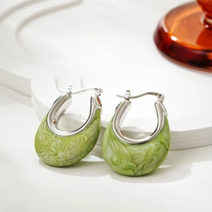 Detailed macro of silver U-shaped hoop earrings with green marbled enamel inlay