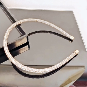 Detail of slim gold headband with sparkling crystals reflected on a black mirror surface