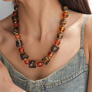 Vue détaillée du collier en perles acryliques ambrées avec intercalaires dorés