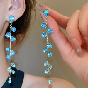 Macro shot of long tassel earrings featuring blue teardrop stones and gold plating