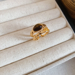Macro shot of gold double-layer ring with brown oval tiger eye stone in a jewelry box