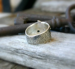 Vintage silver wide ring with dragonfly texture displayed on antique wood and key