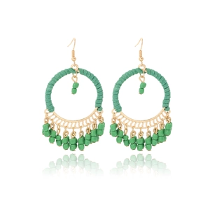 Macro view of bohemian round earrings with green hand-woven beads and gold metal