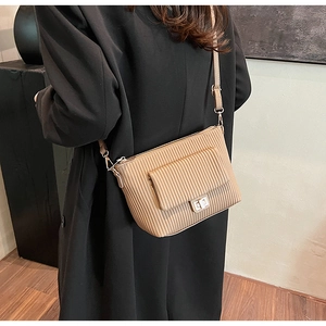 Crossbody bag with pleated leather texture and metal lock shown in a lifestyle setting