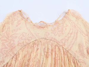 Dettaglio di abito in chiffon floreale con scollo a pieghe e catena di perline argento