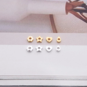 Macro shot of silver and gold beads in heart, star, and flower shapes for DIY jewelry