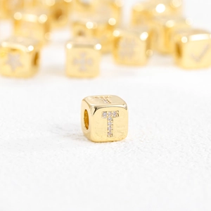 Detailed macro view of 18k gold plated cube bead with zircon letter T inlay