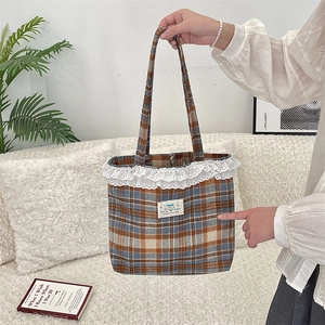 Macro view of vintage plaid tote bag featuring white lace trim and decorative Happy patch