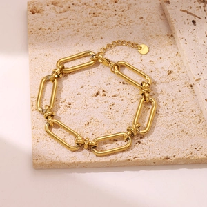Modern gold plated stainless steel chunky chain link bracelet on a beige stone surface
