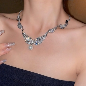 Elegant wing pendant necklace with silver finish and pearls on female neck