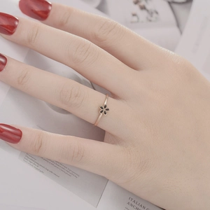 Detail of rose gold flower ring with black enamel petals worn on finger