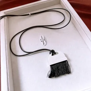 Minimalist long fringe necklace with white arch pendant on red velvet background