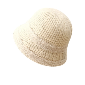 Knitted beige bucket hat for women with ribbed texture and fluffy trim on white background