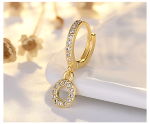 Macro shot of gold hoop earrings with sparkling cubic zirconia on white ceramic surface