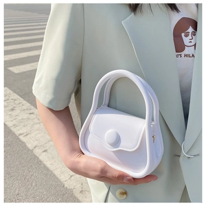 Detail shot of a white mini structured handbag with a round button clasp held by a model
