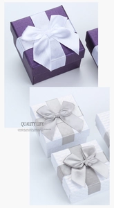 Detail of square jewelry gift boxes with bow ribbons in purple and white textured paper